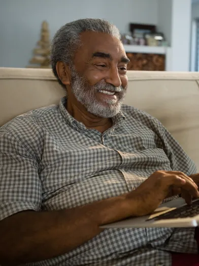 Senior African American man looking at laptop computer while sitting on couch
