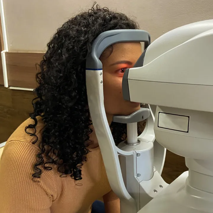 A Black woman gets her eyes examined by a machine