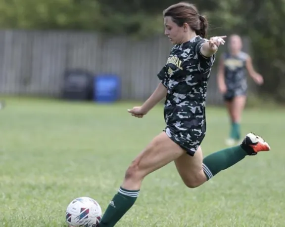 Girl playing soccer on a field.